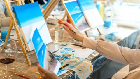 A woman painting an ocean scene at a Kauai paint and sip class