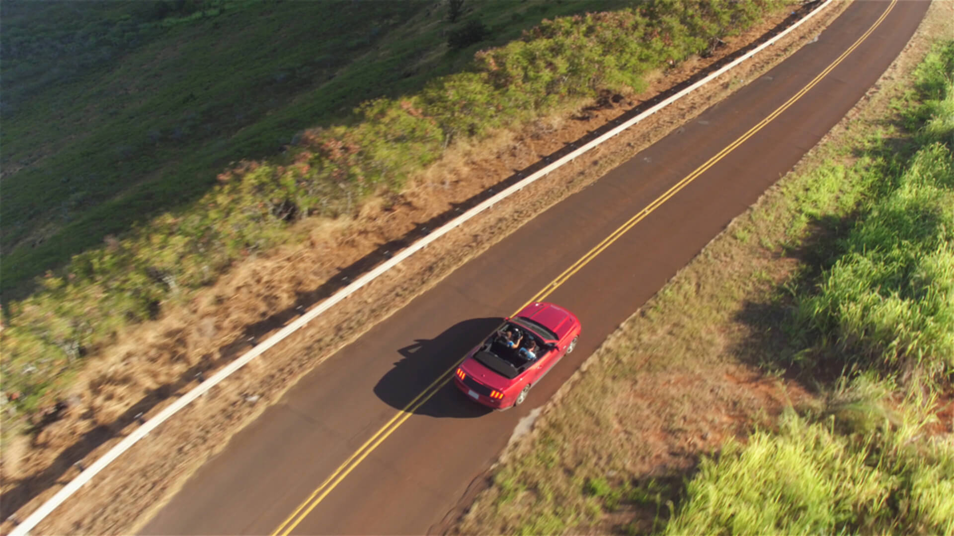 A convertible car driving along the coast of Kauai