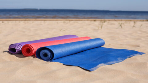 Three rolled yoga mats on a beach on Kauai